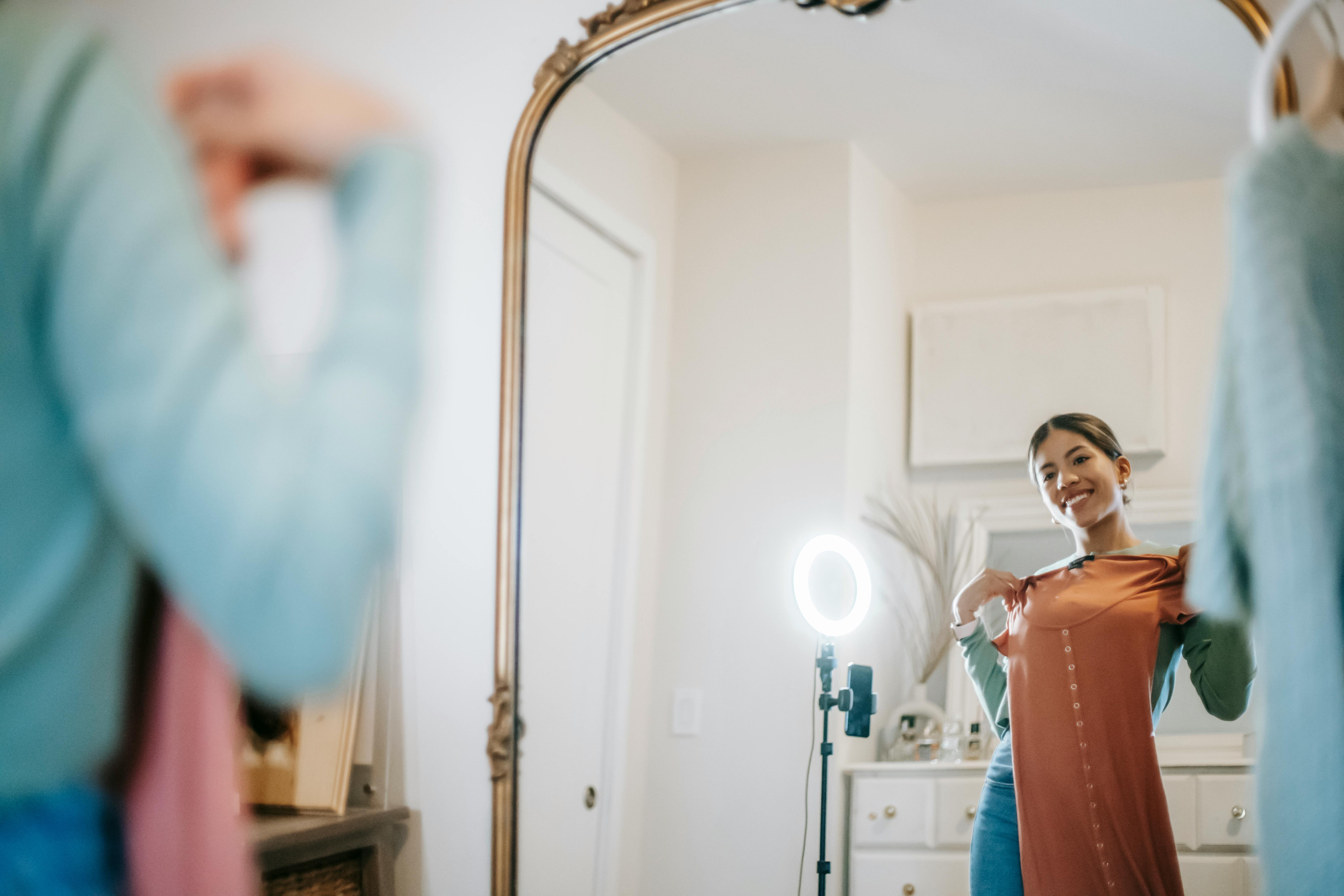 smiling ethnic woman filming vlog on mobile while demonstrating dress