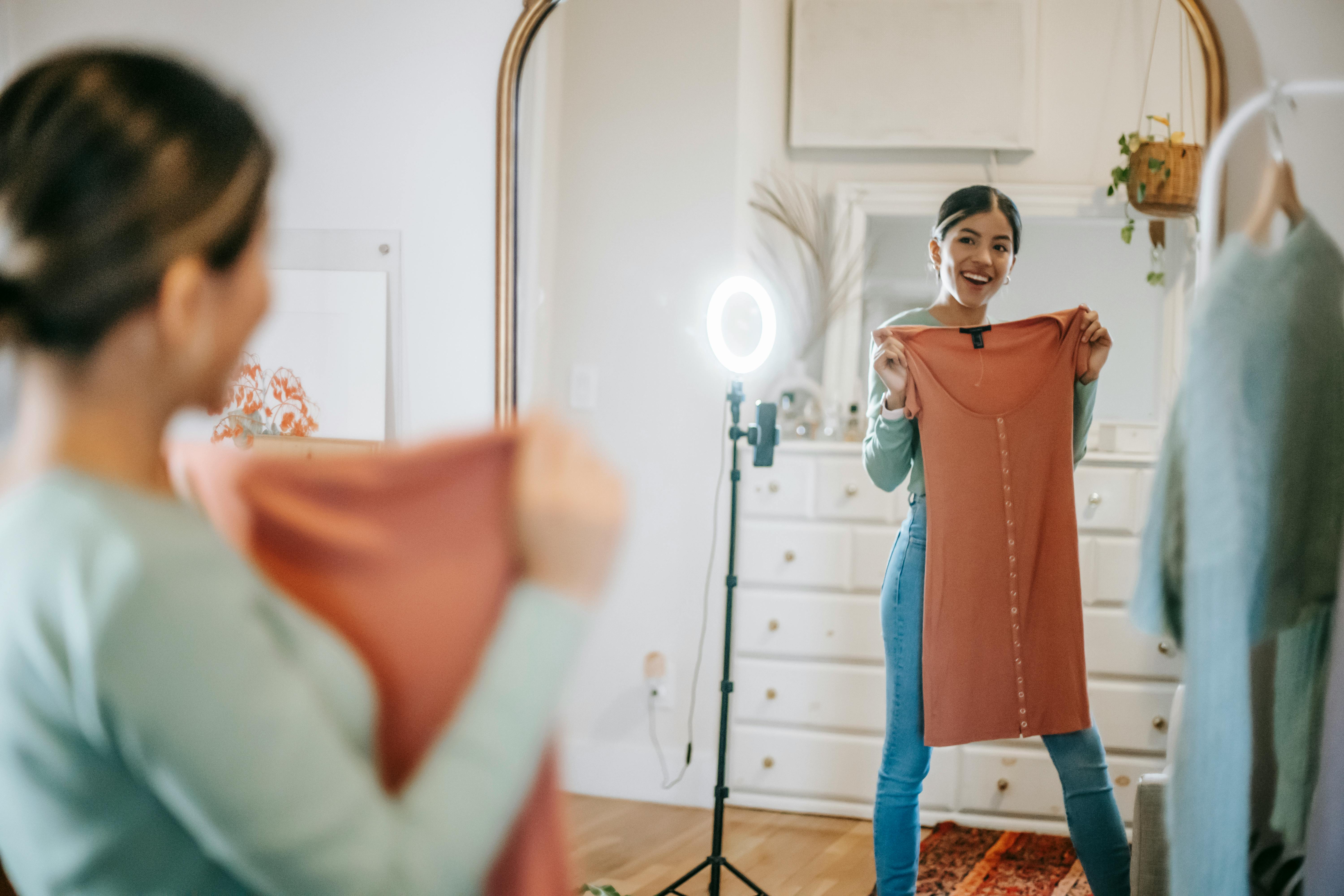 happy ethnic lady filming vlog on mobile while demonstrating dress