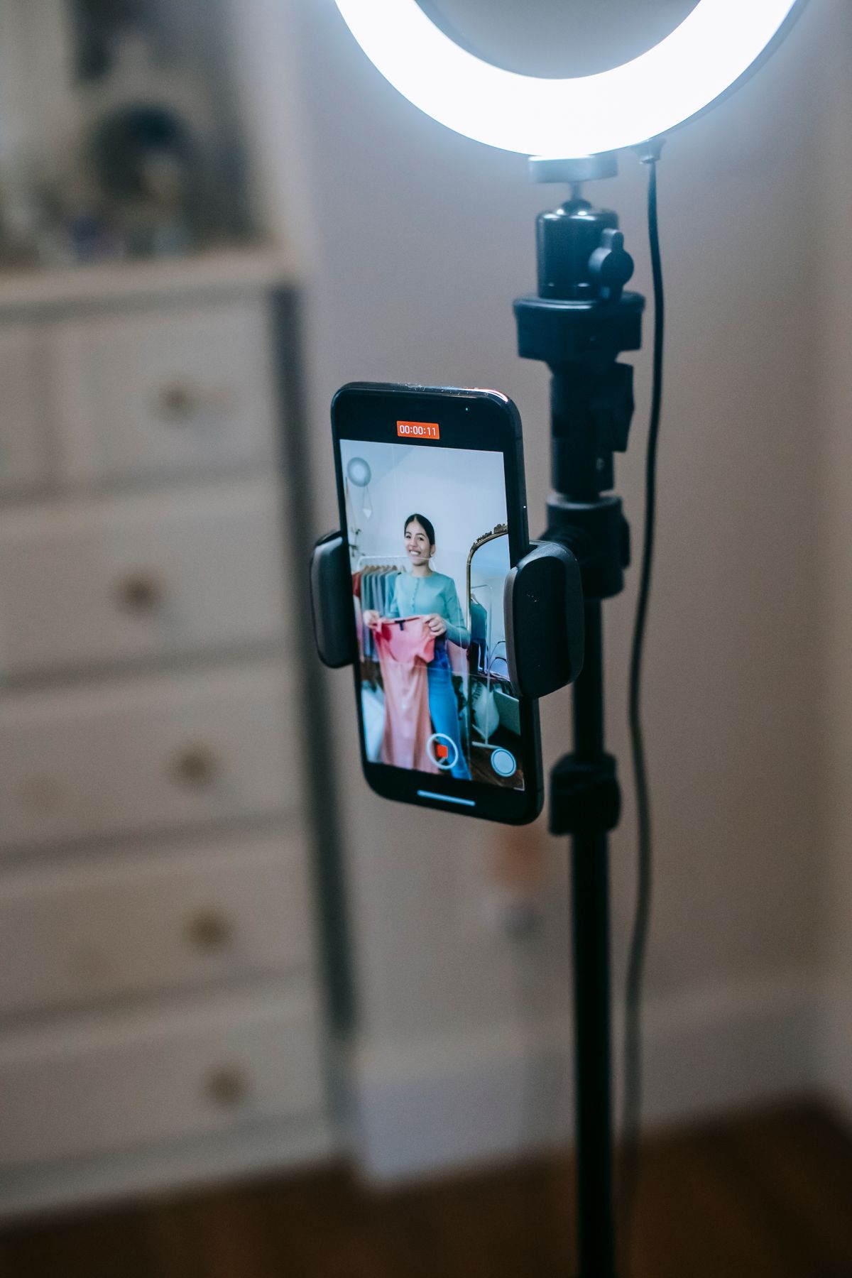 Creator filming a fashion video with a smartphone and ring light