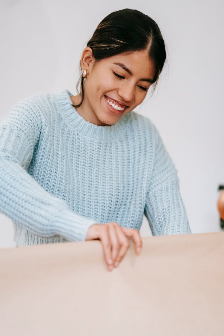 Cheerful Ethnic Craftswoman With Wrapping Paper At Home