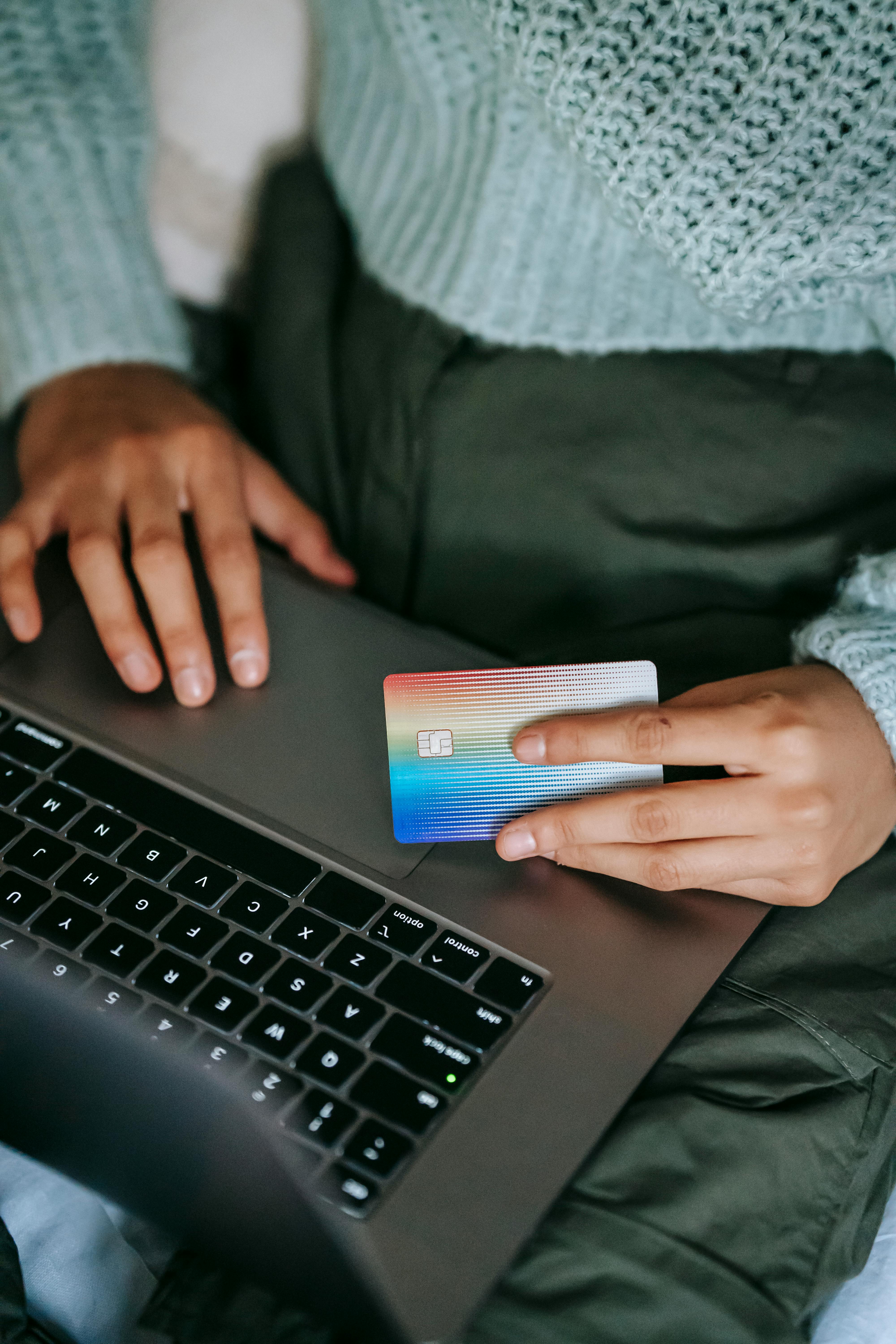 crop ethnic buyer with plastic card shopping online on laptop