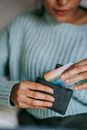Crop anonymous ethnic female with credit card and leather case resting at home in daytime