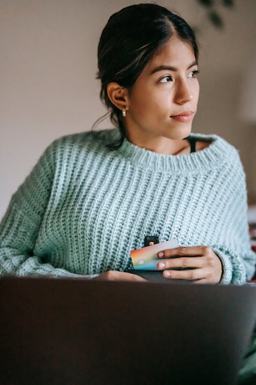 Женщина в сером вязаном свитере с белым смартфоном