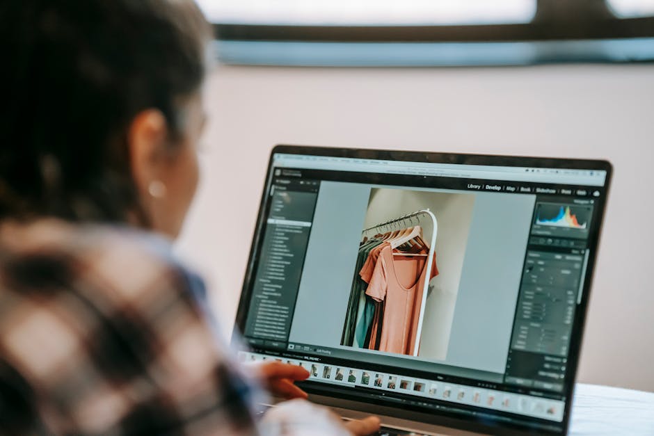 Back view of crop anonymous ethnic female freelancer retouching photo with outfit on netbook while working in house