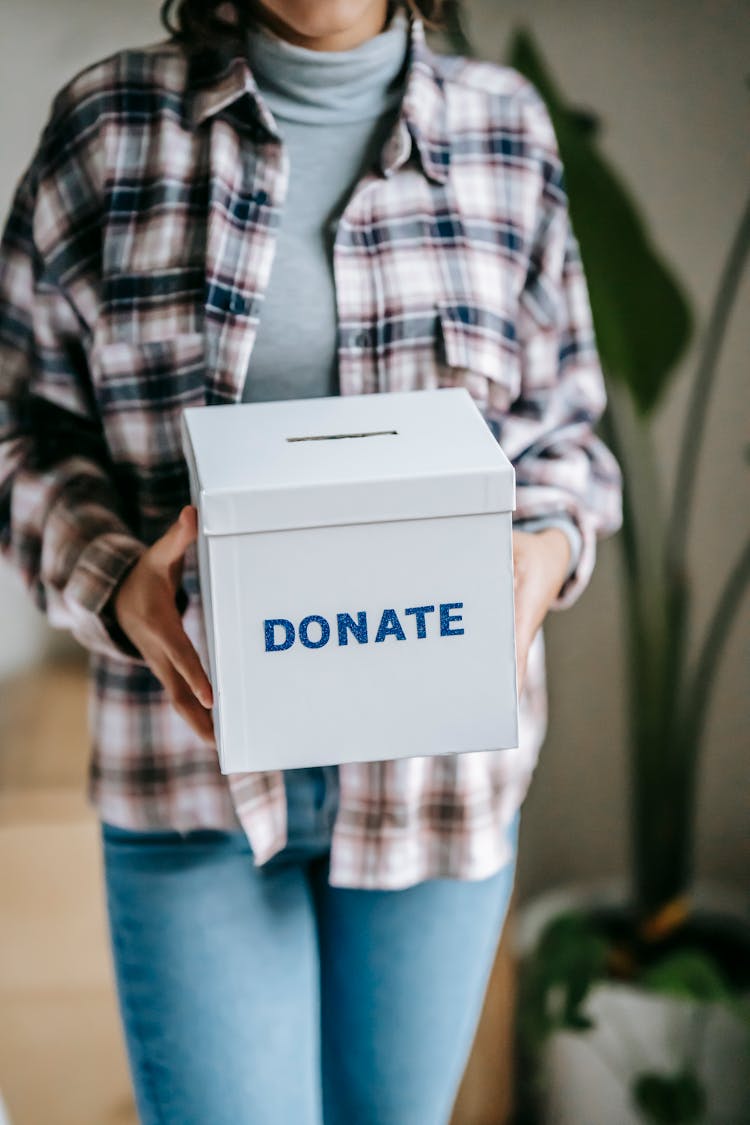 Woman Holding Box With Inscription Donate In Light Room