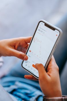 Close-up of hands holding a smartphone displaying a financial app with stock data.