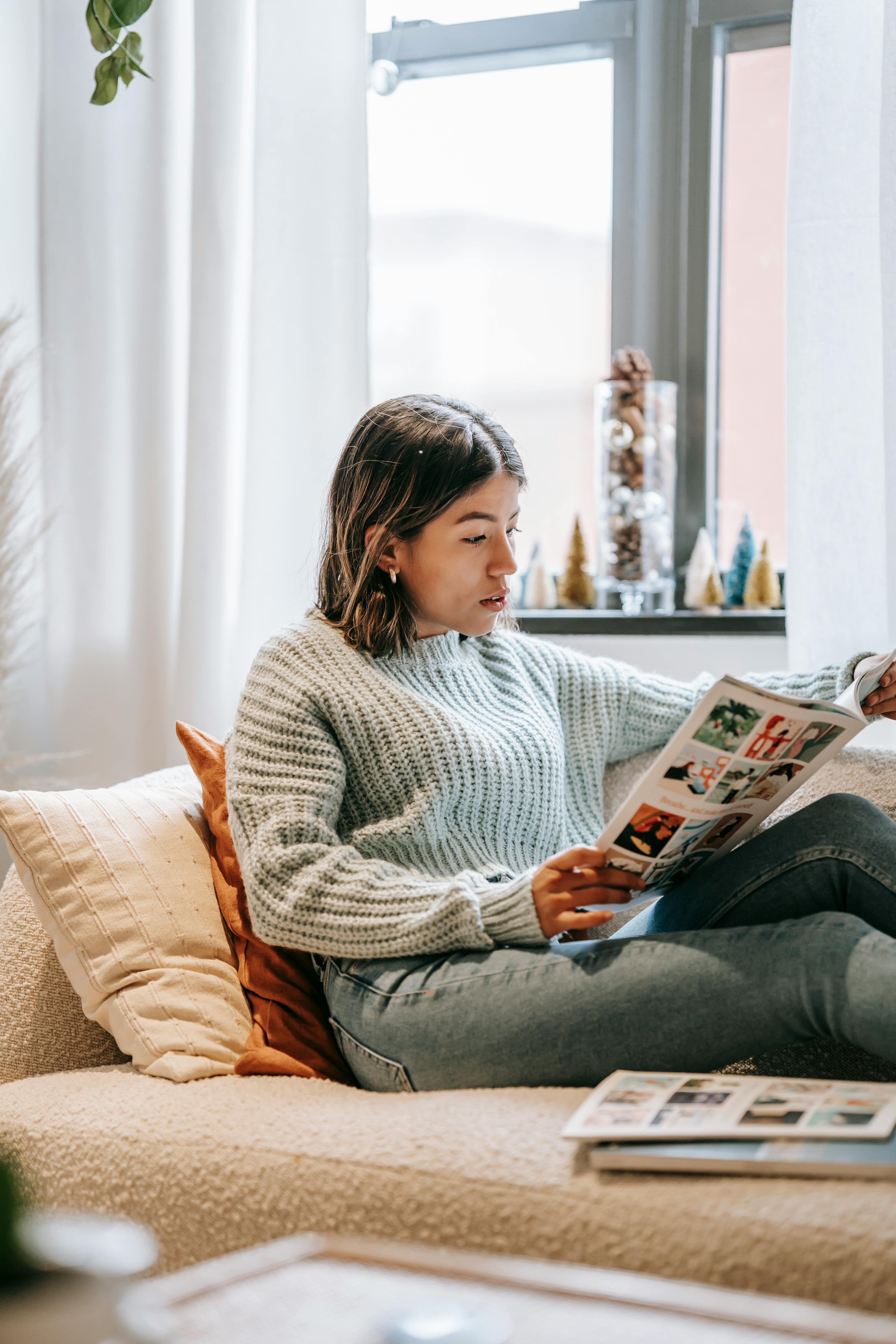 serious ethnic woman reading magazine in living room