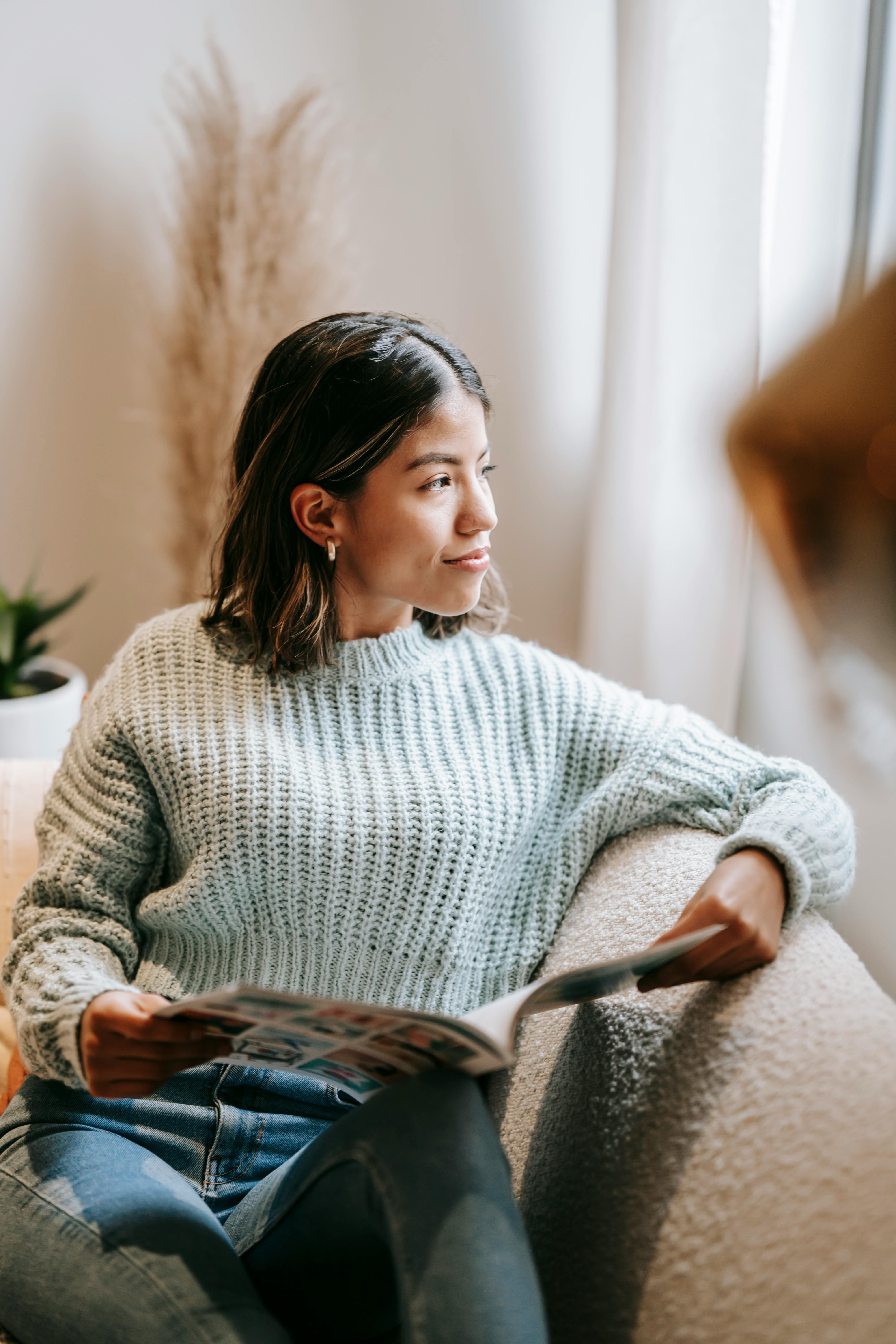 smiling ethnic woman on couch with opened magazine