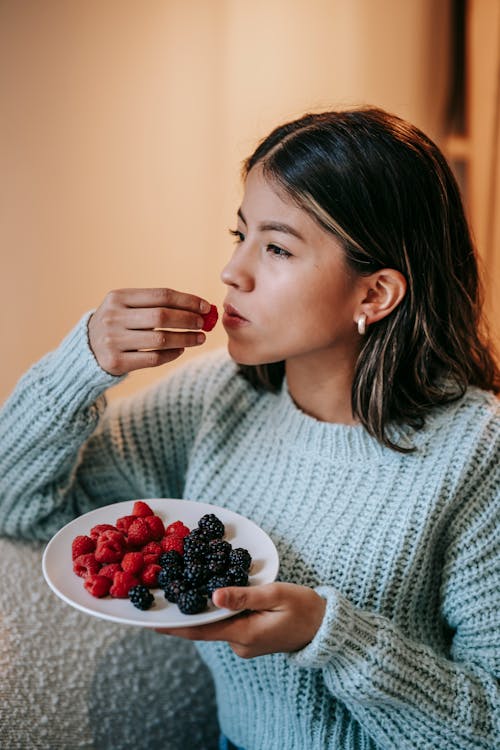 Free Thoughtful ethnic female eating ripe berries Stock Photo