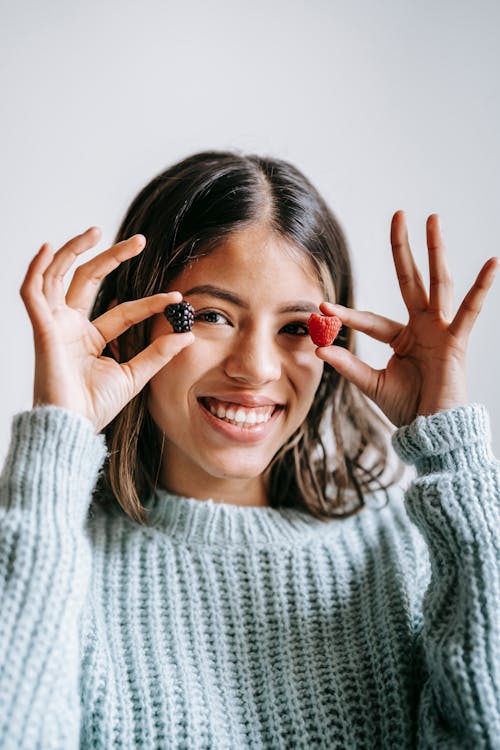 Smiling ethnic woman with blackberry and raspberry in fingers