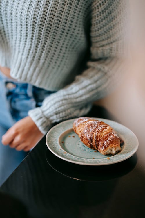 Woman standing near plate with crispy croissant