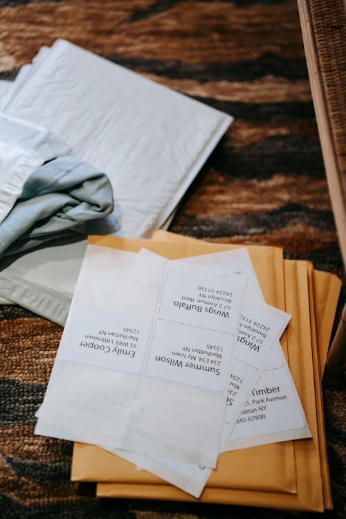 High angle of shipping parcel bags on carpet on floor with papers with address in light room