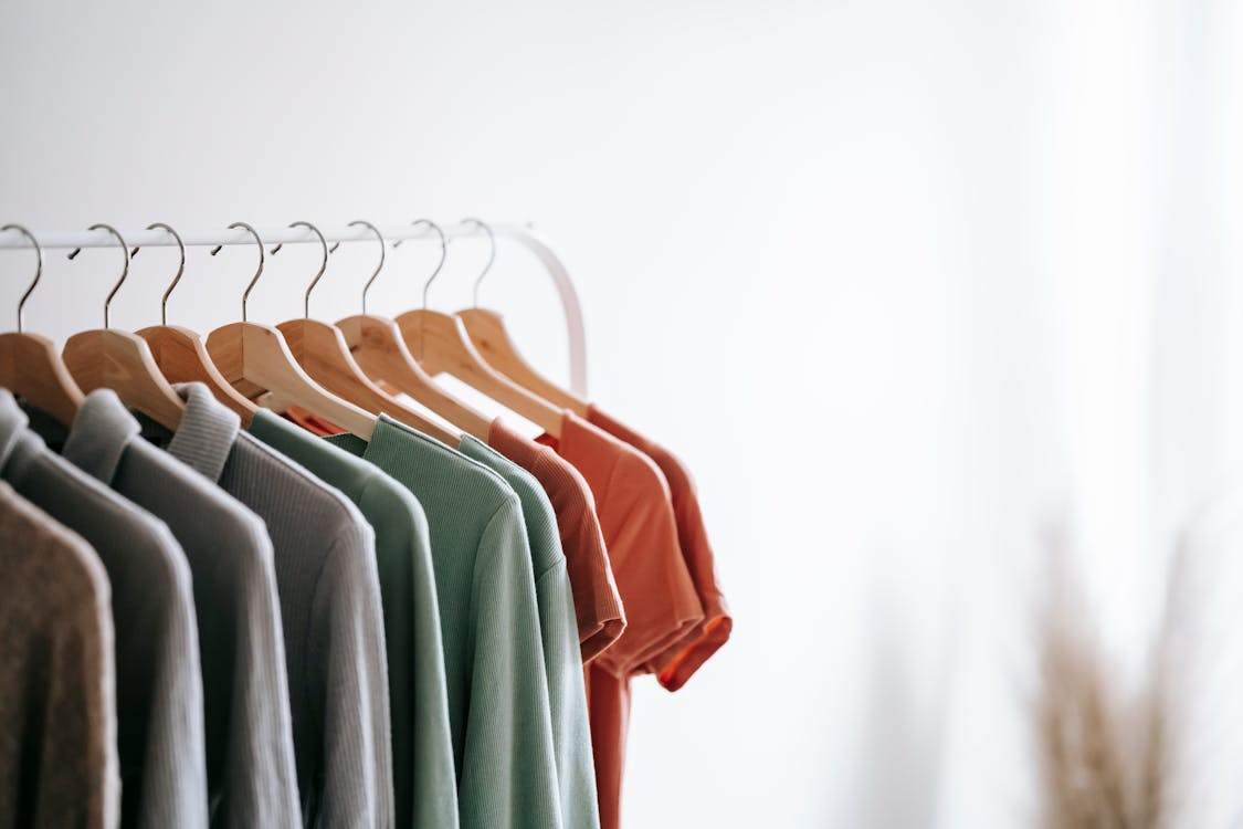 Free Interior of light apartment with different clothes on wooden hangers in wardrobe near white walls Stock Photo