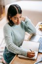 Latin American woman taking notes in notebook near netbook