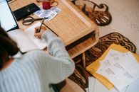 Faceless ethnic female writing information in notebook near envelope parcels