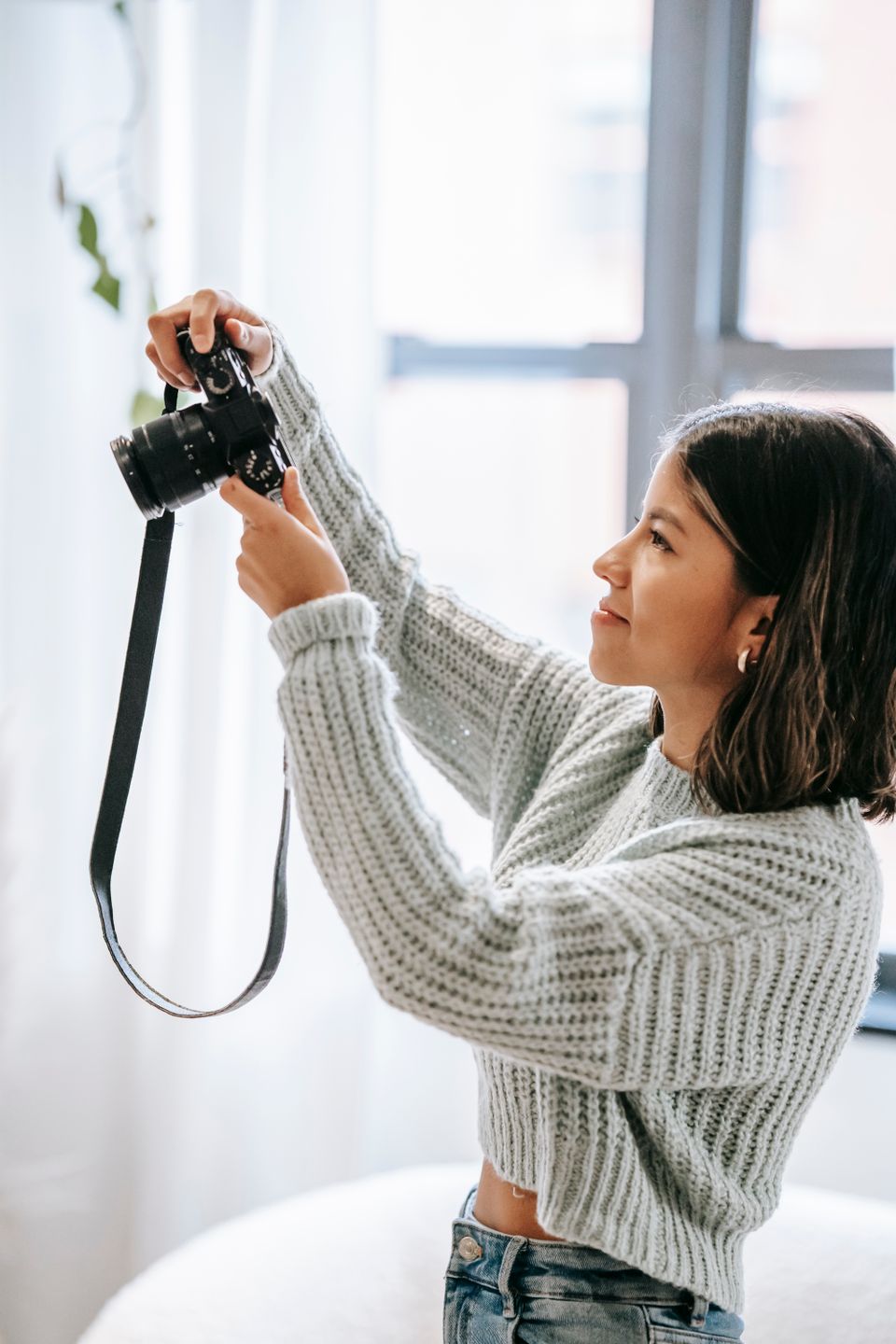 Fotograf som riktar kameran mot ett fönster i ett ljust hem