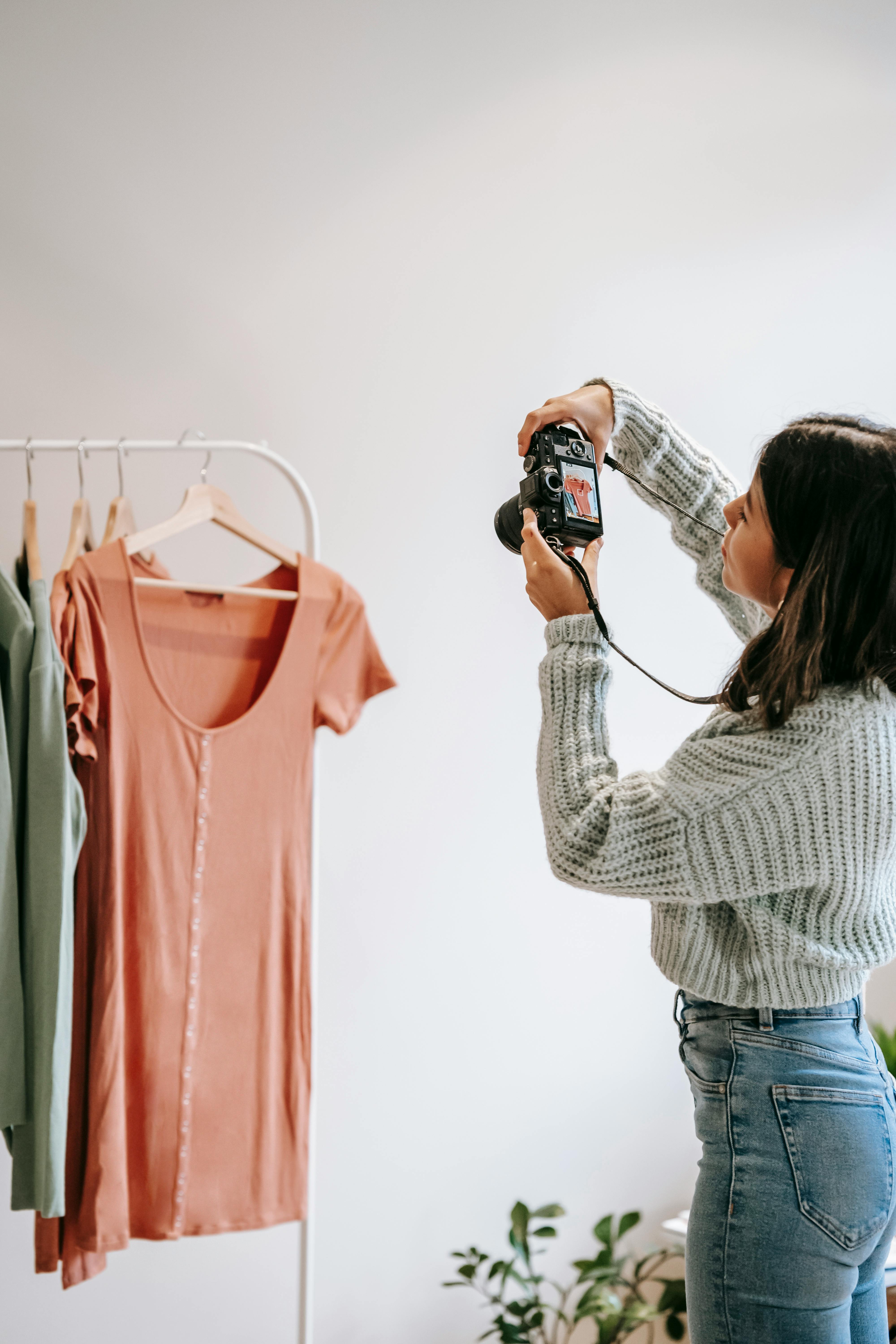 crop ethnic photographer taking photo of apparel on camera