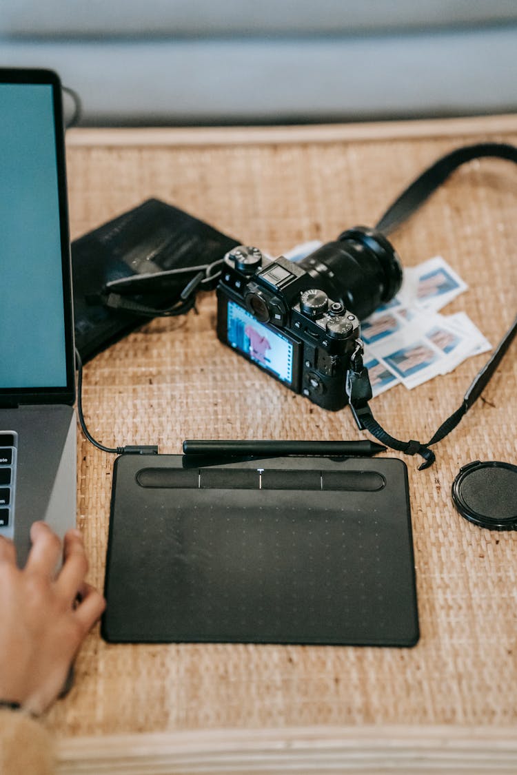 Crop Photographer Using Laptop Near Photo Camera On Table