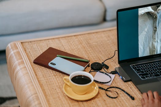 A relaxing home office setup with a laptop, coffee, and notebook on a woven table.