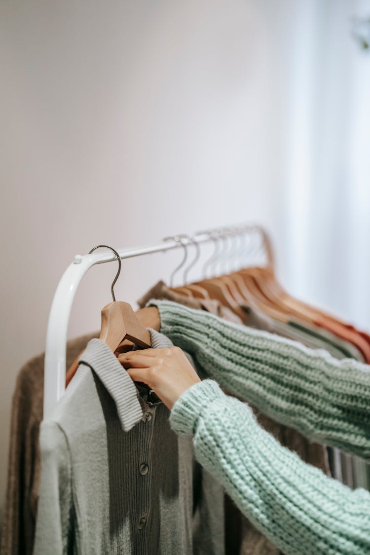 Crop Woman Choosing Outfit On Rack On White Background