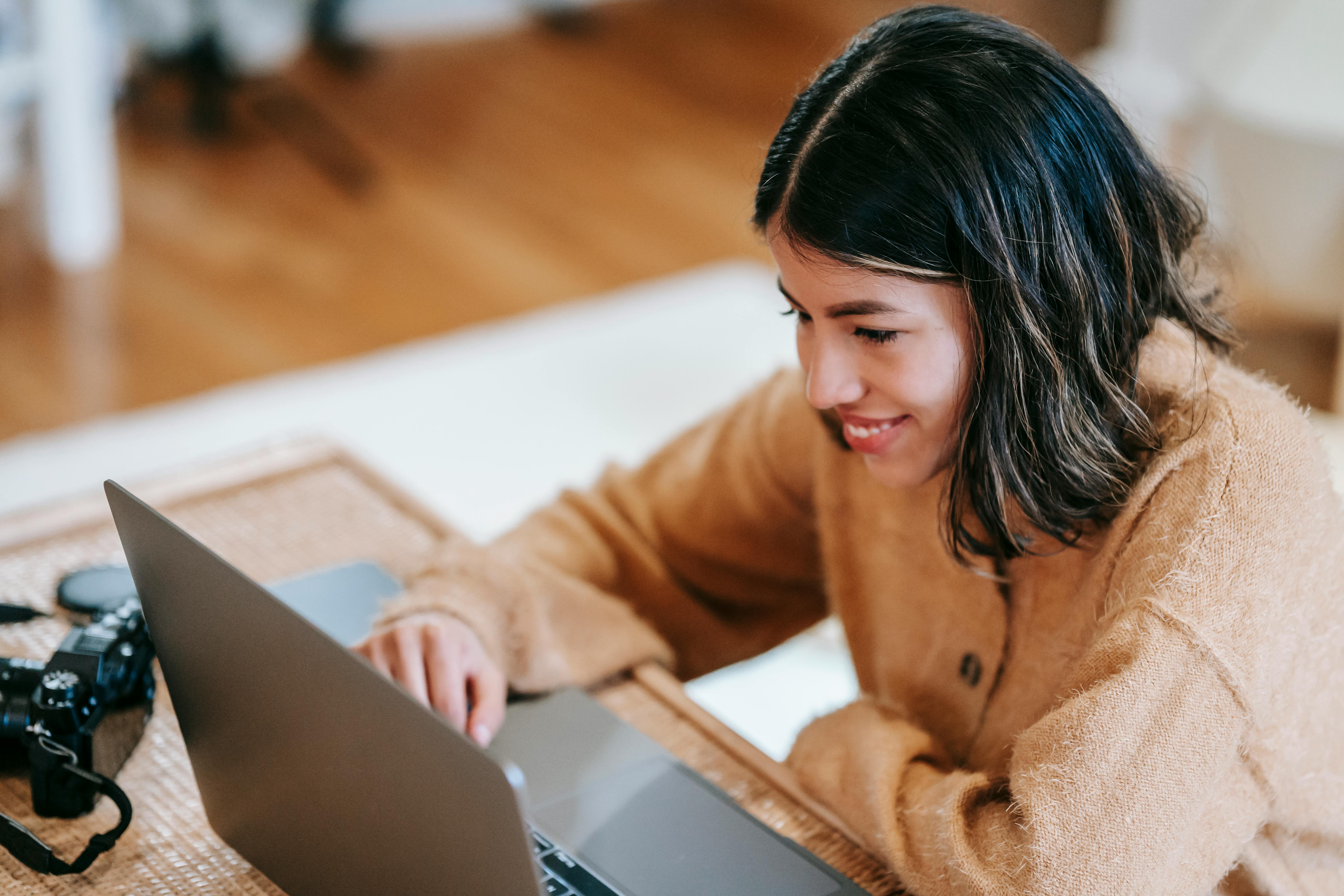 cheerful ethnic photographer using laptop at home