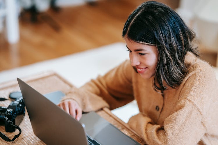 Cheerful Ethnic Photographer Using Laptop At Home