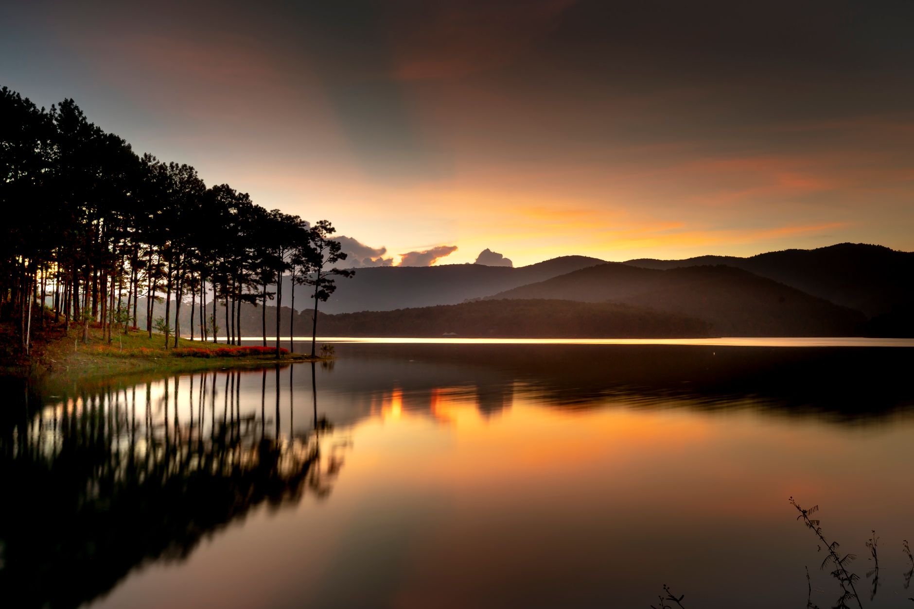 Peaceful sunrise view of Tuyen Lam Lake in Dalat, Vietnam with stunning reflections and silhouettes.