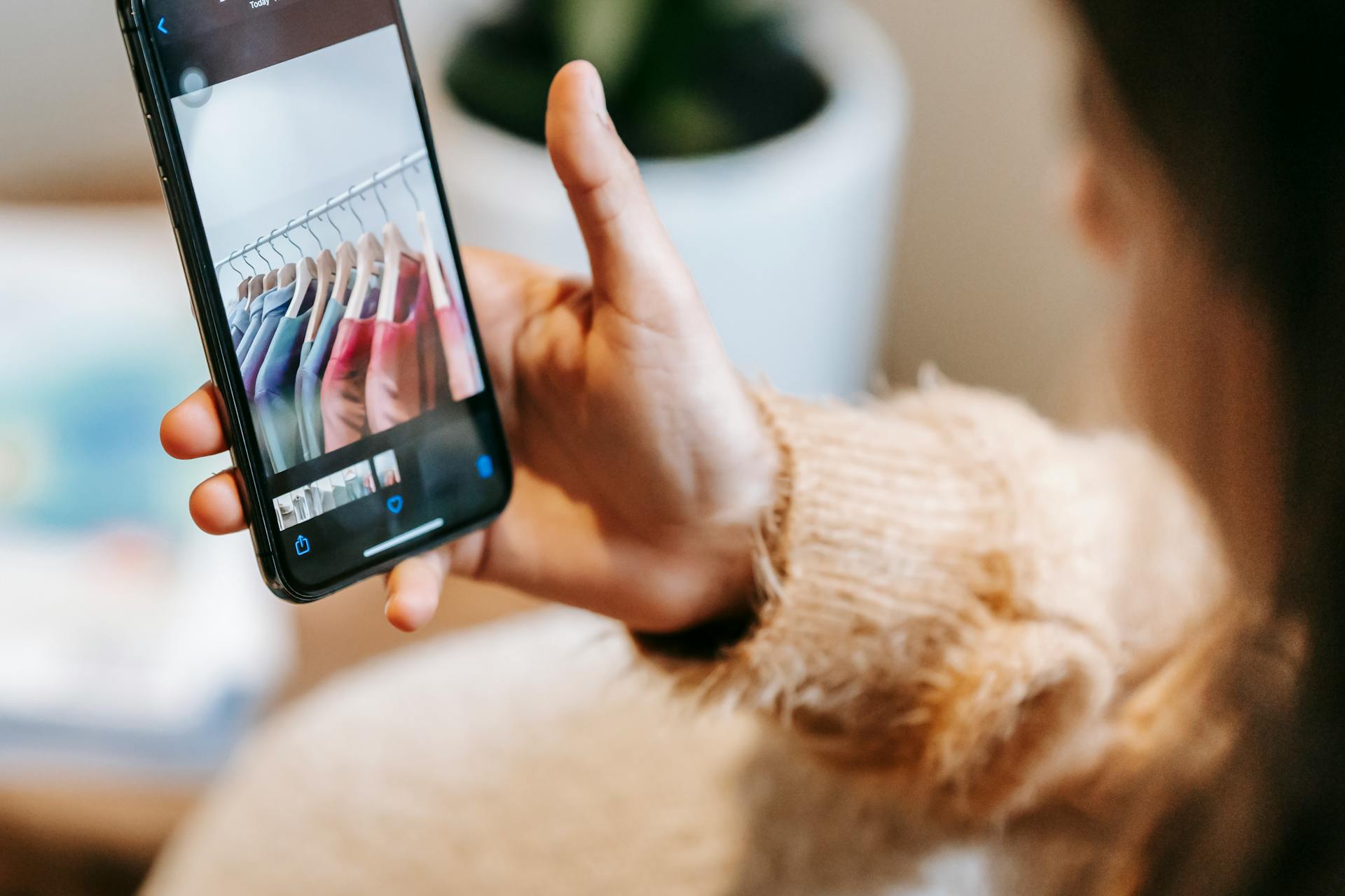 Faceless female looking at photos of wardrobe on phone