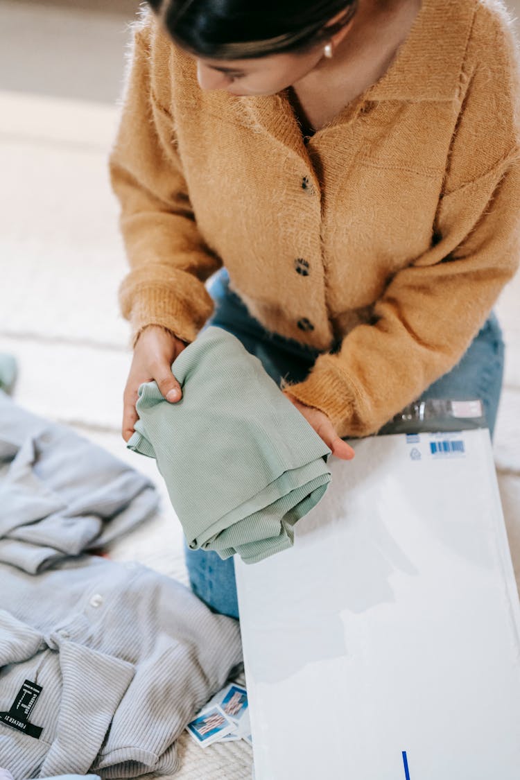 Unrecognizable Female Packing Clothes In Parcel Bag For Shipping