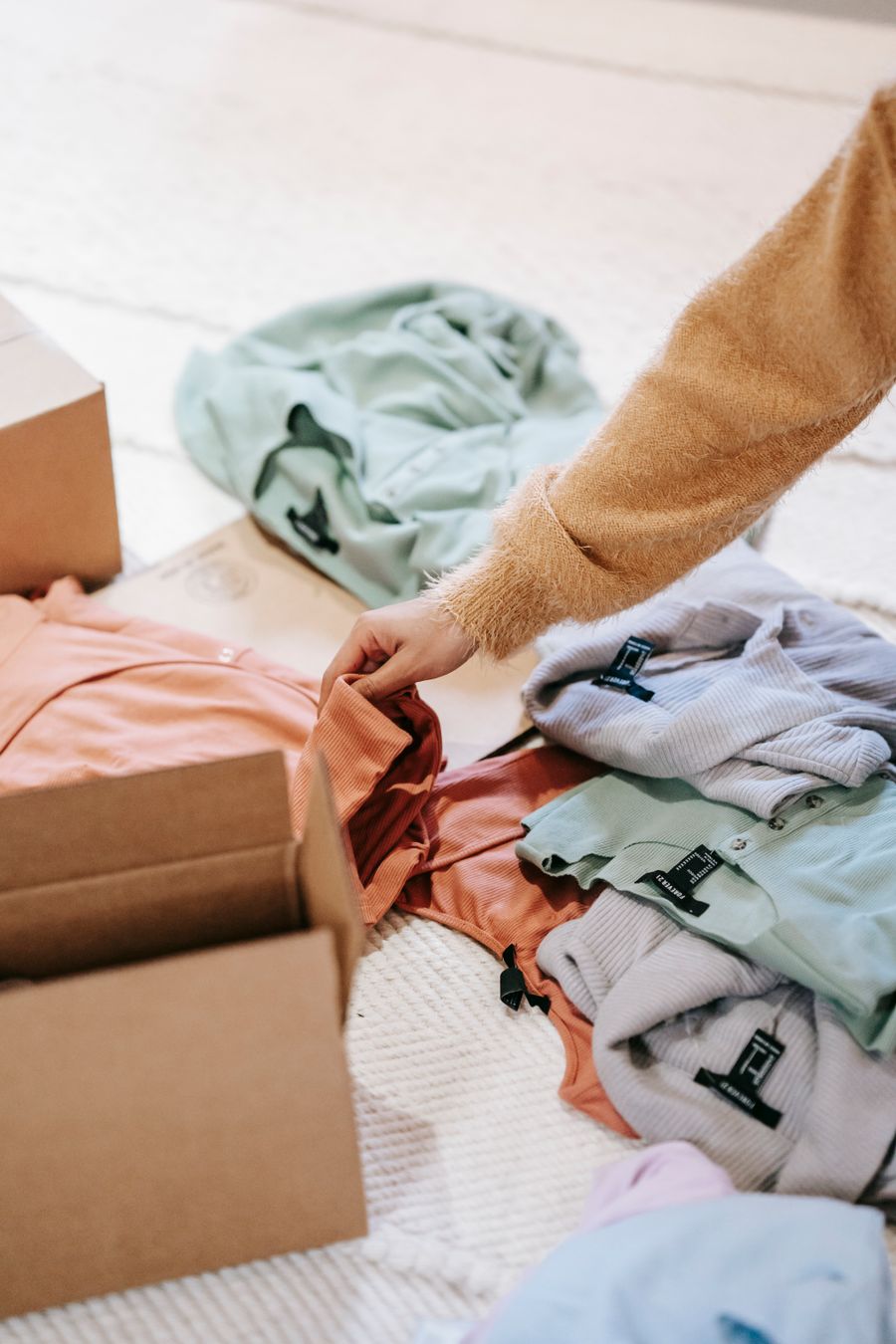 Person sorting household clothes into cardboard boxes