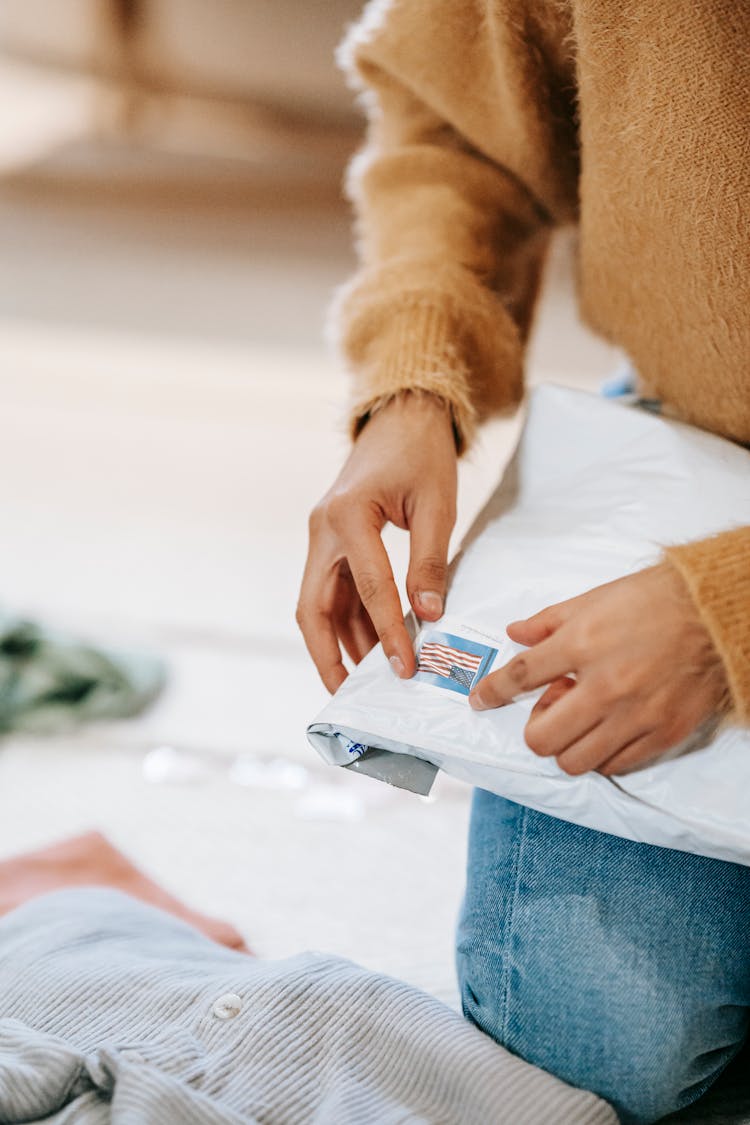 Anonymous Female Putting Stamp On Shipping Parcel Bag