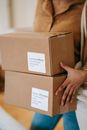 Crop unrecognizable woman carrying parcels in post office
