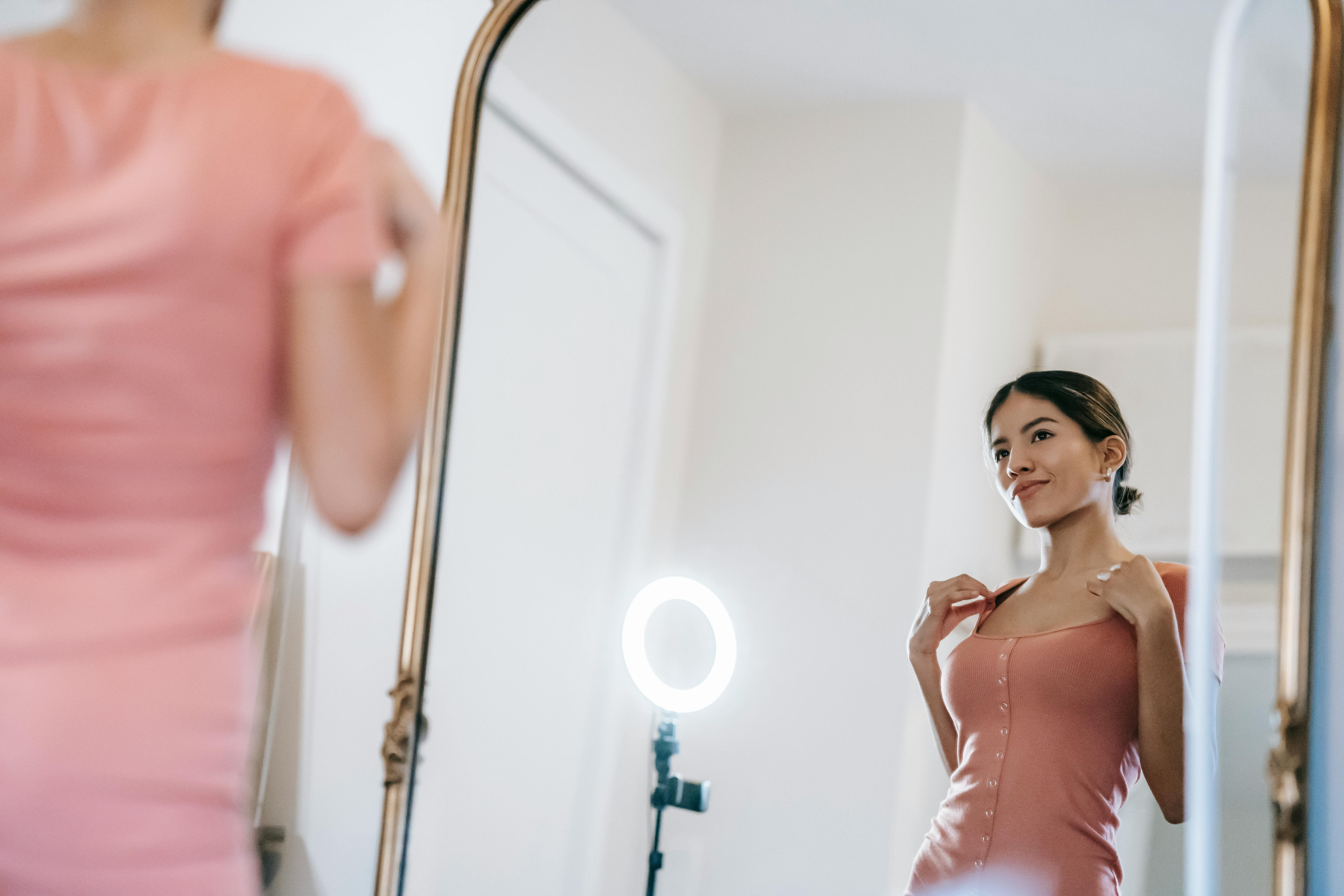attractive woman looking in mirror against ring lamp