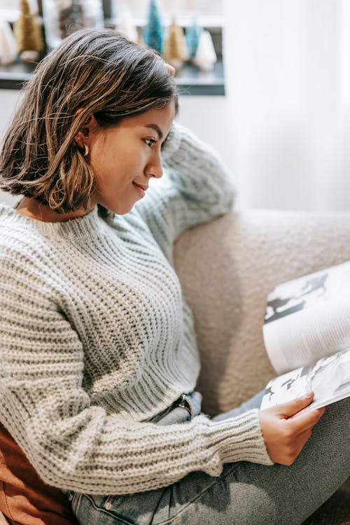 Smiling woman reading magazine on sofa