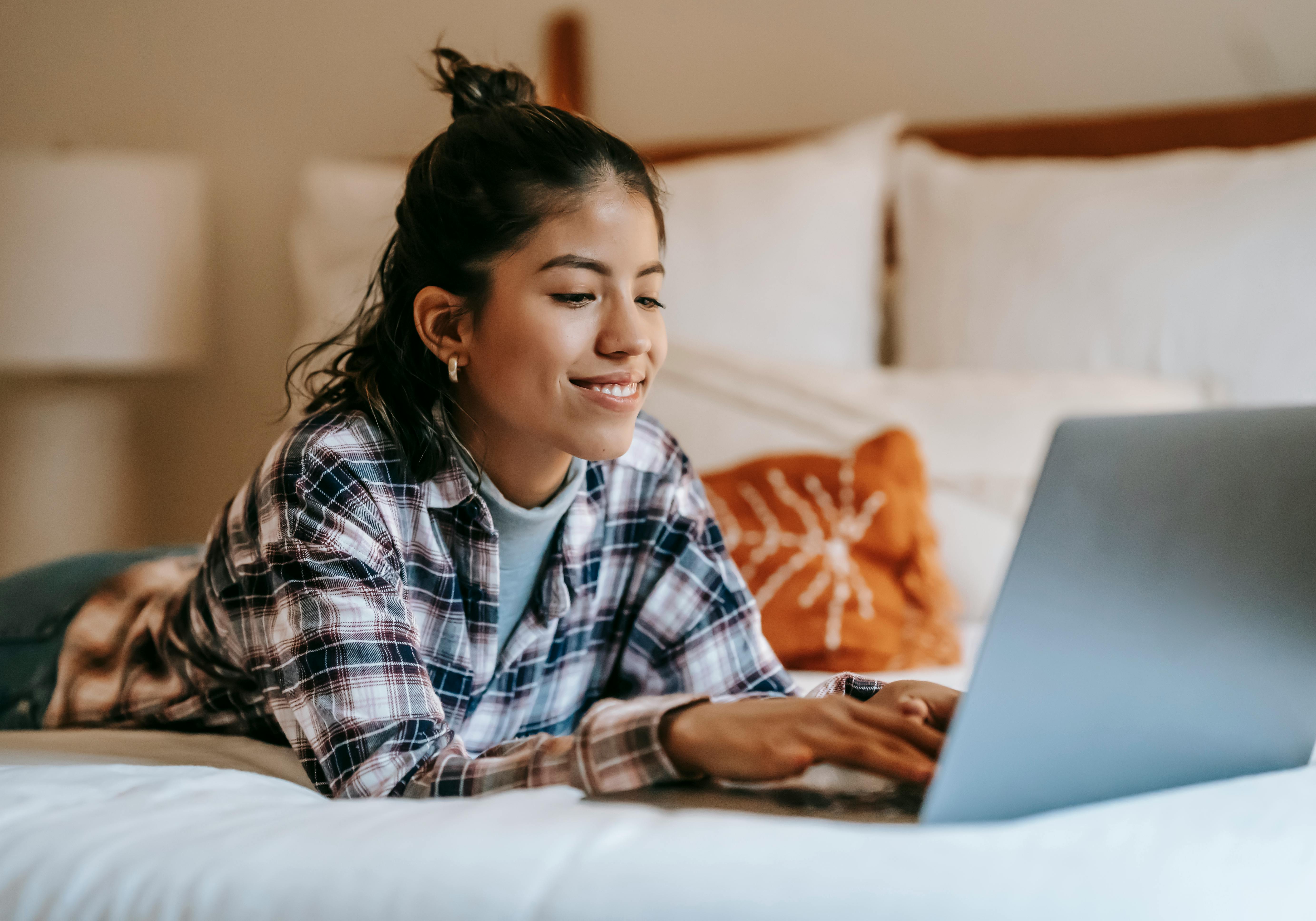 cheerful young ethnic woman typing on laptop