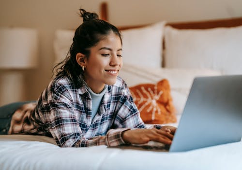 Free Cheerful young ethnic woman typing on laptop Stock Photo