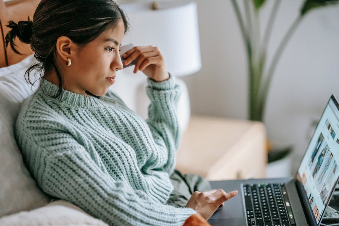 Free Side view of crop concentrated young ethnic female using touchpad of netbook and shopping online Stock Photo