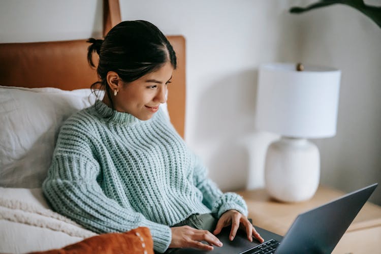 Happy Ethnic Woman Surfing Internet On Laptop While Using Touchpad