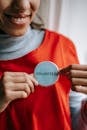 Smiling ethnic woman showing volunteer sign on red apron