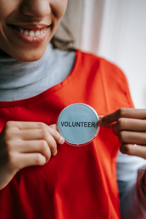 Free Smiling ethnic woman showing volunteer sign on red apron Stock Photo