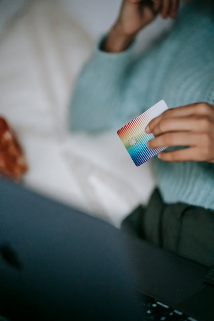 Woman Checking Credit Card While Using Laptop