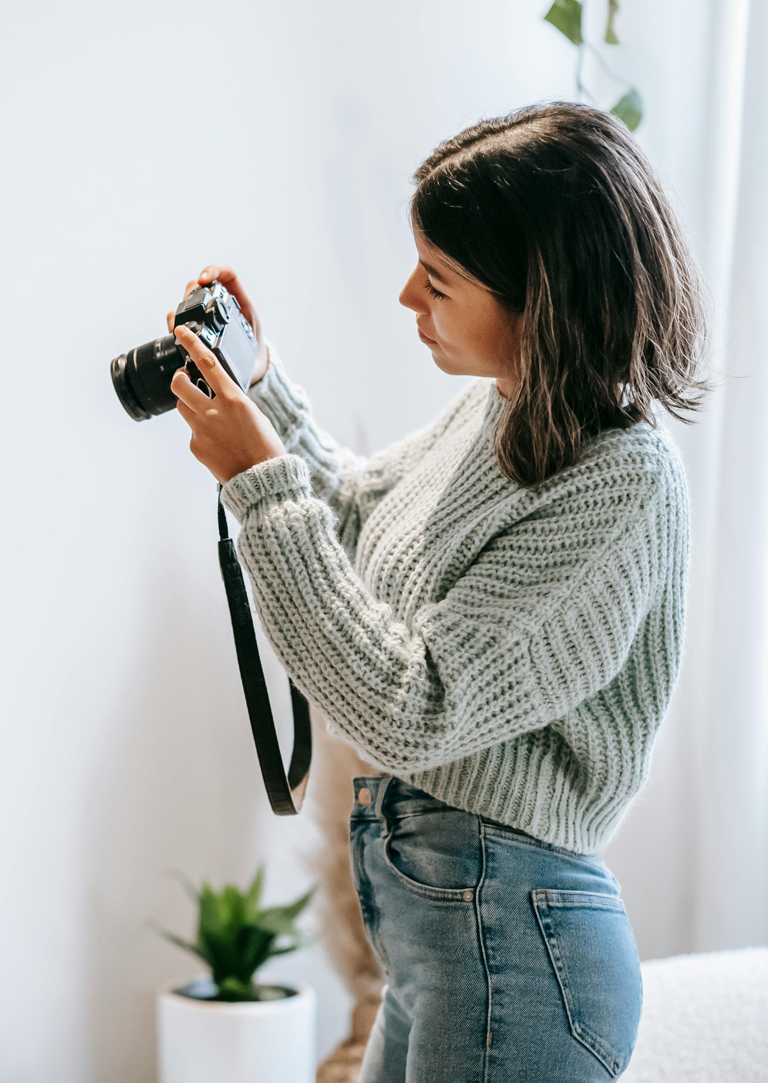 young woman checking modern photo camera