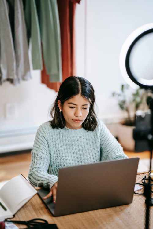 Free From above of young ethnic female with dark hair using netbook at table with planner on blurred background Stock Photo
