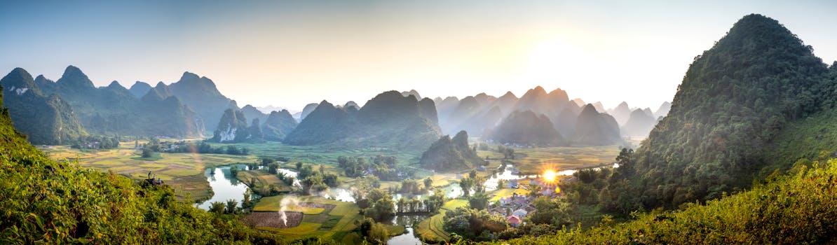 Panoramic view of Cao Bang's lush valley and mountains at sunrise, with mist and sunbeams illuminating the landscape.
