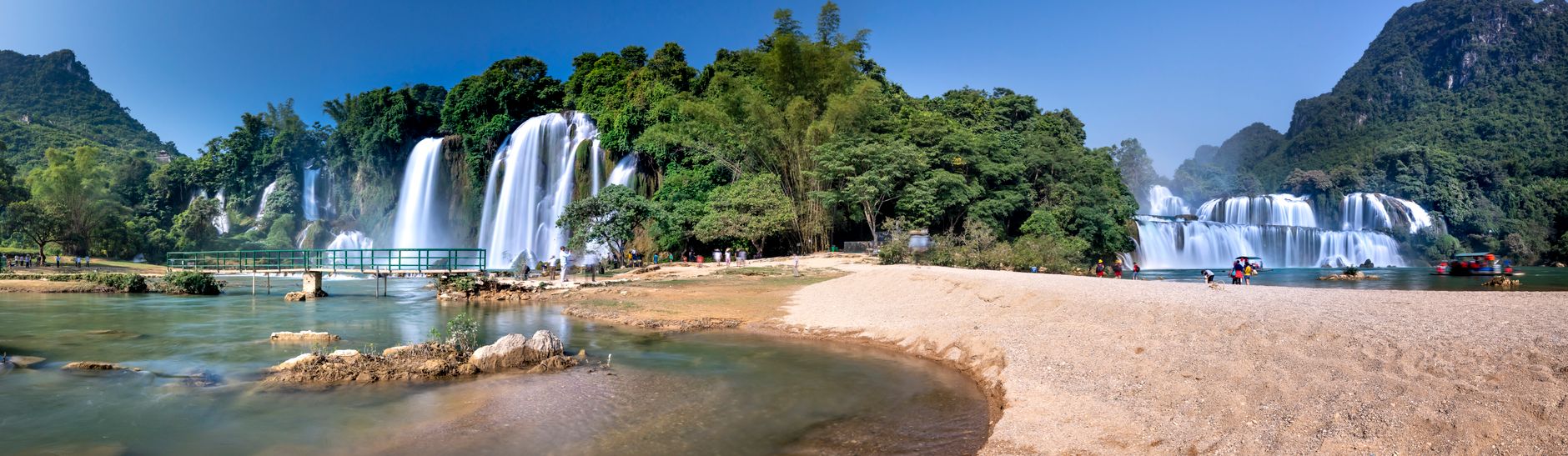 Beautiful view of Ban Gioc Waterfall surrounded by lush jungle and clear water.