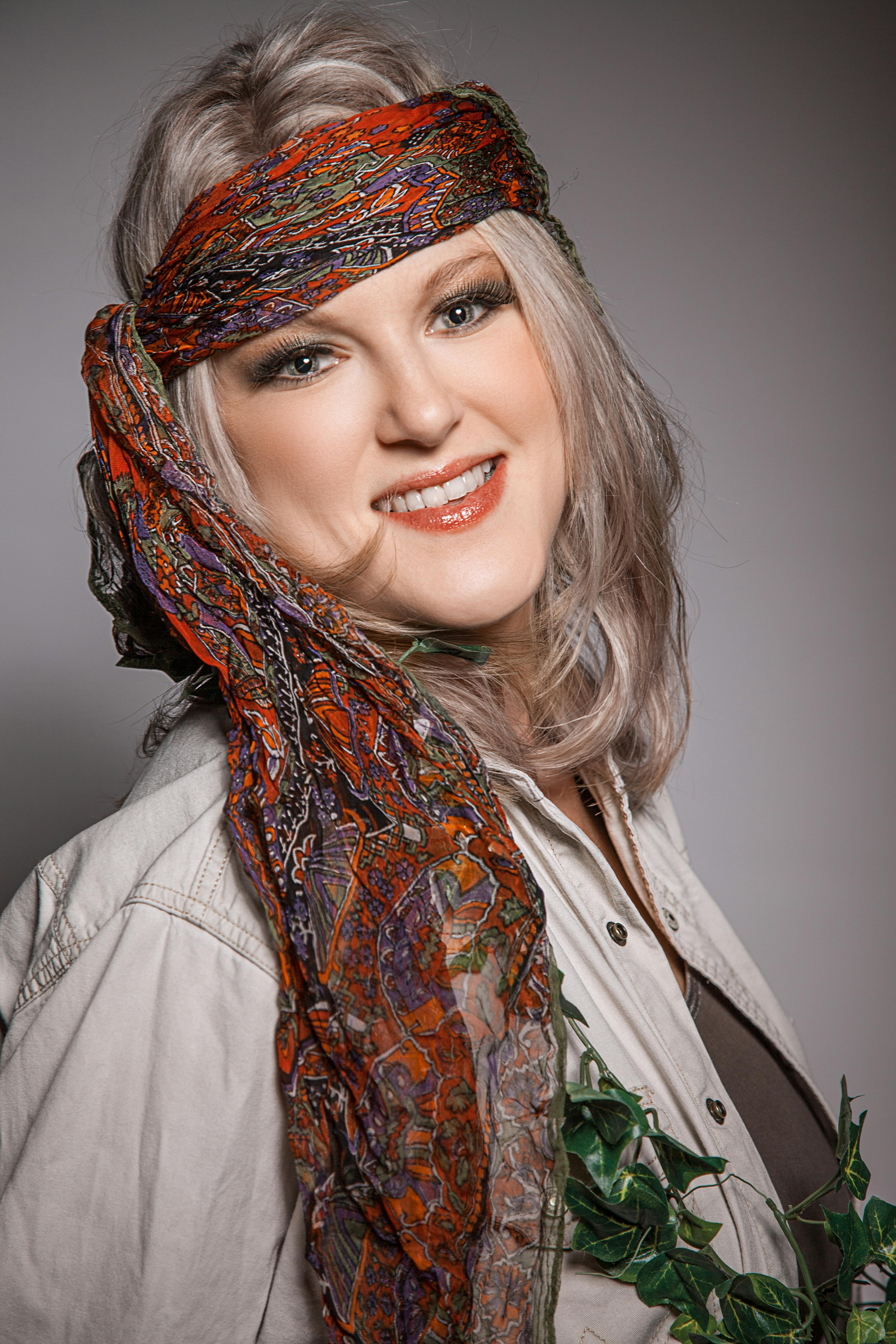 Charming adult woman with a vibrant headscarf, exuding style and happiness in a studio portrait.
