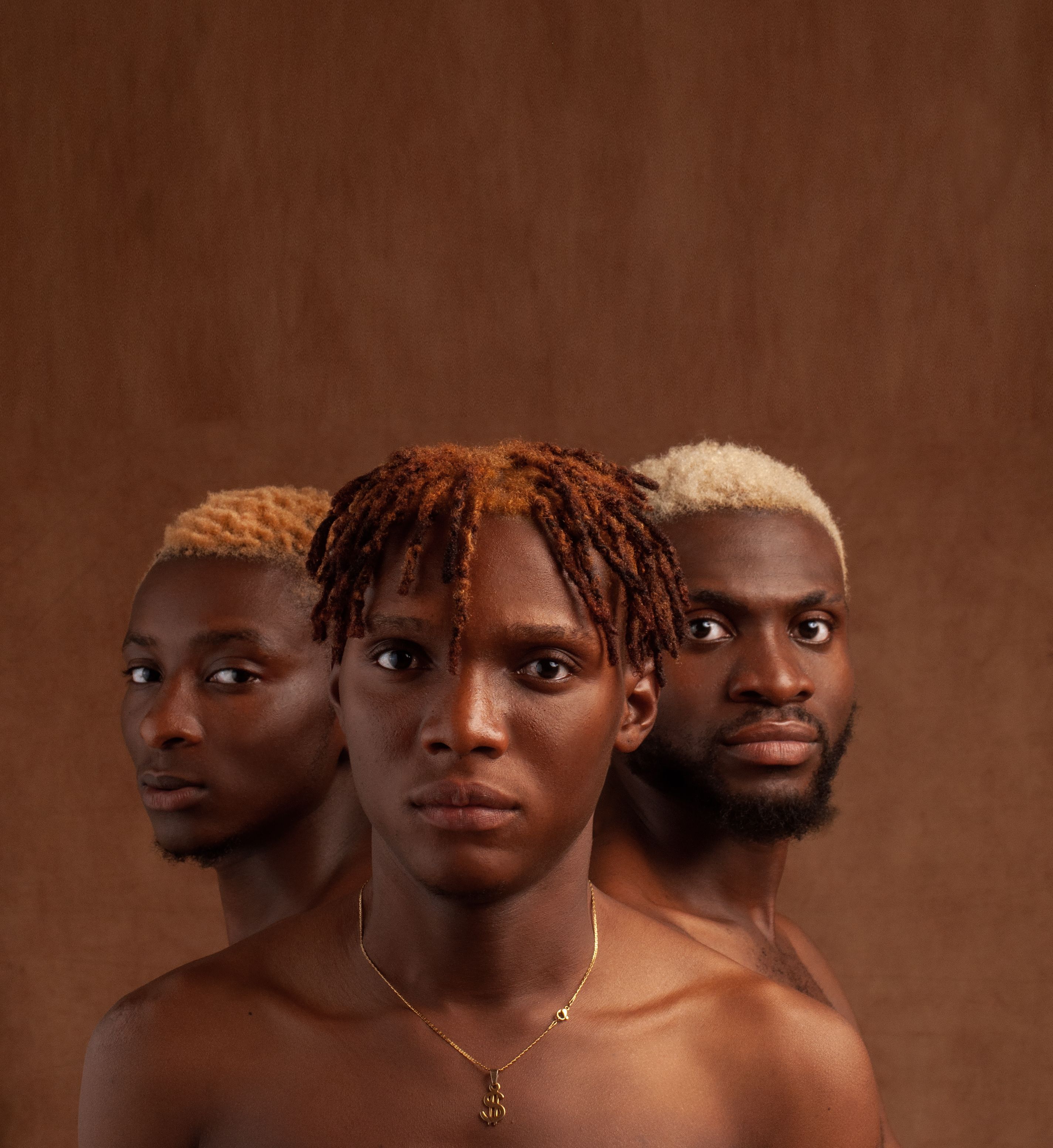 Artistic portrait of three black men with diverse hairstyles on a brown background.