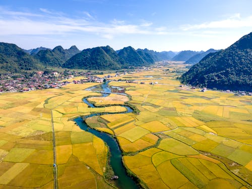 Agricultural fields and wavy river against mountains in countryside