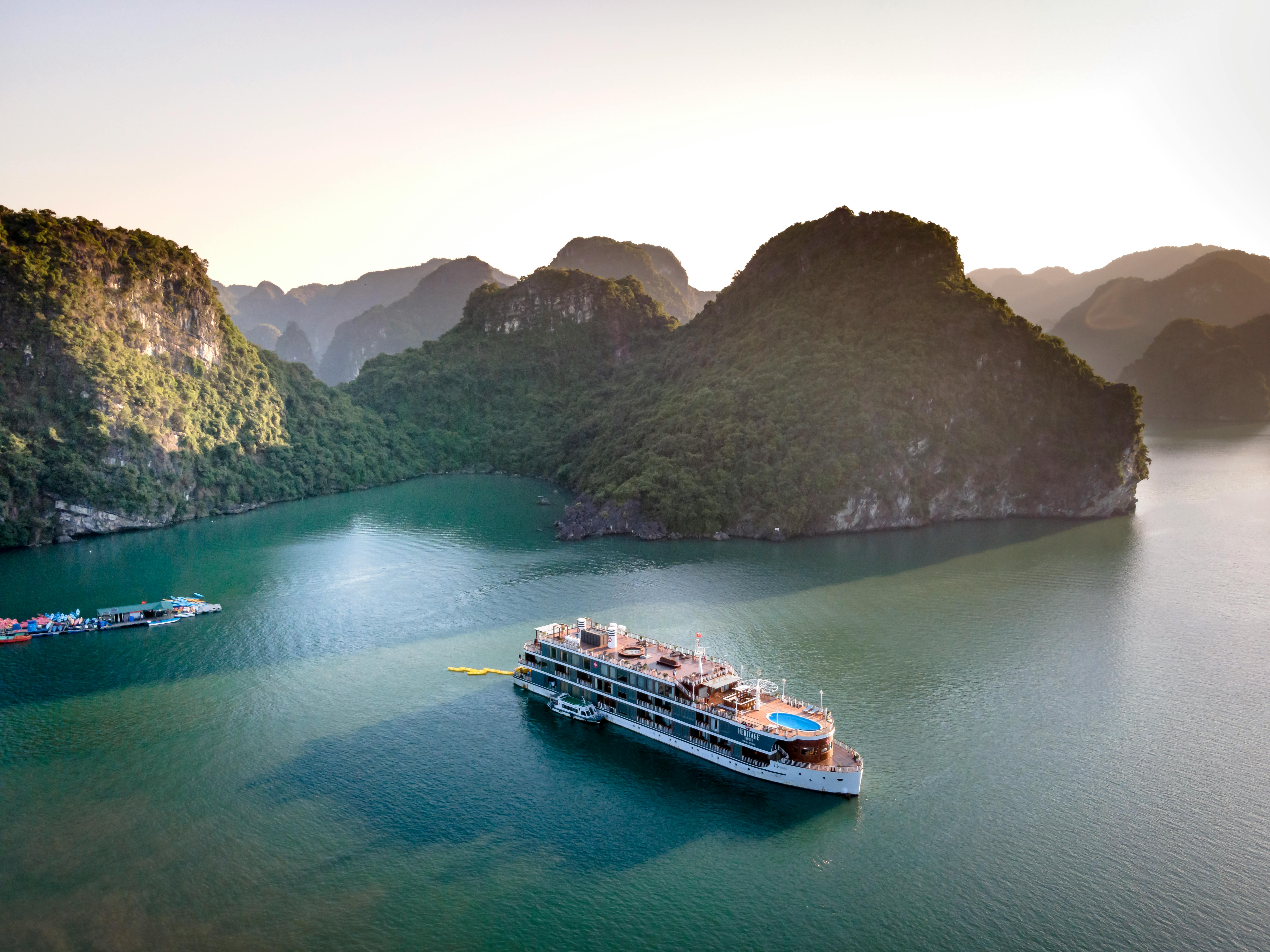 Aerial view of motor ship sailing on rippled ocean against high mounts under light sky