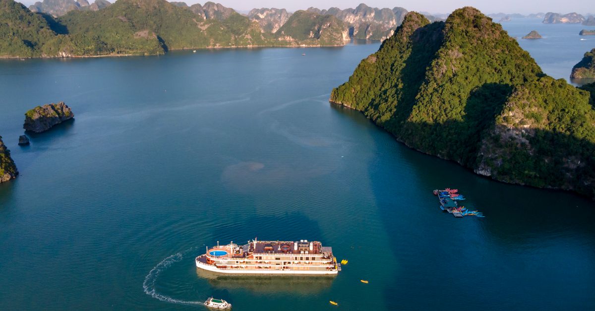 Aerial view of a cruise ship navigating through Ha Long Bay's limestone islands